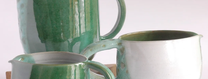 Créations en céramique artisanale, trois pichets émaillés aux teintes vertes et blanches, élégance contemporaine.