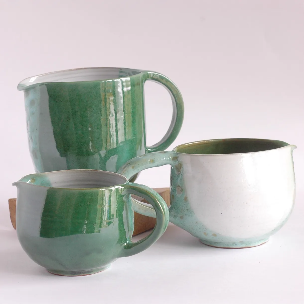 Créations en céramique artisanale, trois pichets émaillés aux teintes vertes et blanches, élégance contemporaine.