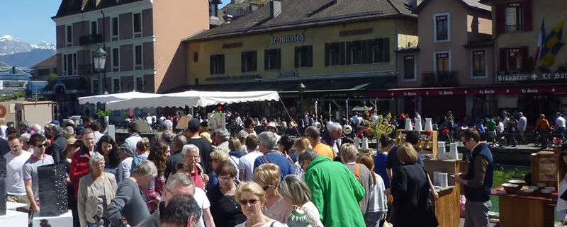 Marché convivial à Annecy, où l'artisanat local et la poterie s'épanouissent sous un ciel ensoleillé.