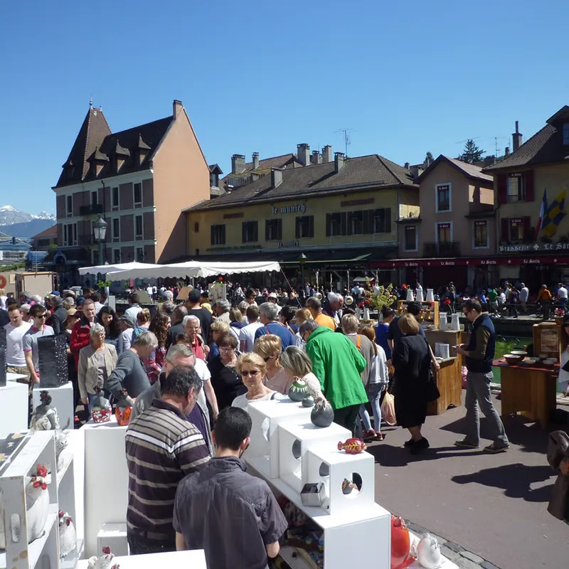 Marché convivial à Annecy, où l'artisanat local et la poterie s'épanouissent sous un ciel ensoleillé.