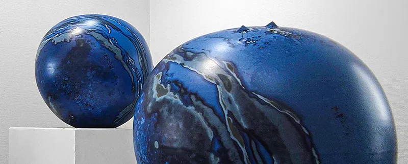 Sculptures en céramique aux teintes bleu profond, affichant des motifs fluides et modernes, exposition artistique contemporaine.