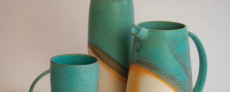 Groupe de céramiques artisanales en grès émaillé, aux teintes turquoise et orange, élégantes et modernes.