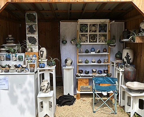 Stand d'artisans au marché, présentant des créations en céramique colorées et modernes, ambiance conviviale et artisanat local.