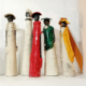 Sculptures en céramique colorée représentant des silhouettes élégantes, exposées dans un cadre artistique convivial.
