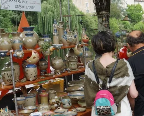 Stand de poterie lors d'un marché convivial, mettant en avant des créations en grès utilitaire aux teintes naturelles.