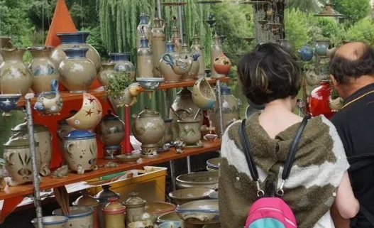 Stand de poterie lors d'un marché convivial, mettant en avant des créations en grès utilitaire aux teintes naturelles.
