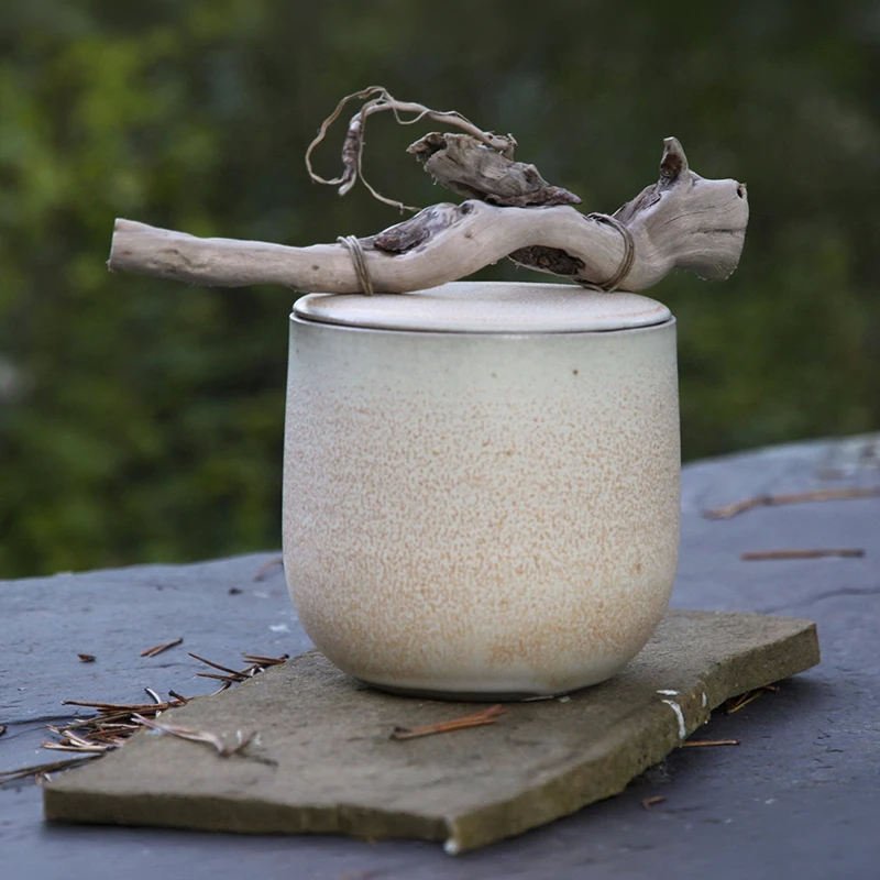 Récipient en céramique artisanale, émaillé aux teintes naturelles, avec une touche organique grâce à une branche décorative.