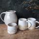 Pichets et mugs en céramique artisanale, décor géométrique sobre, créant une ambiance chaleureuse et élégante.