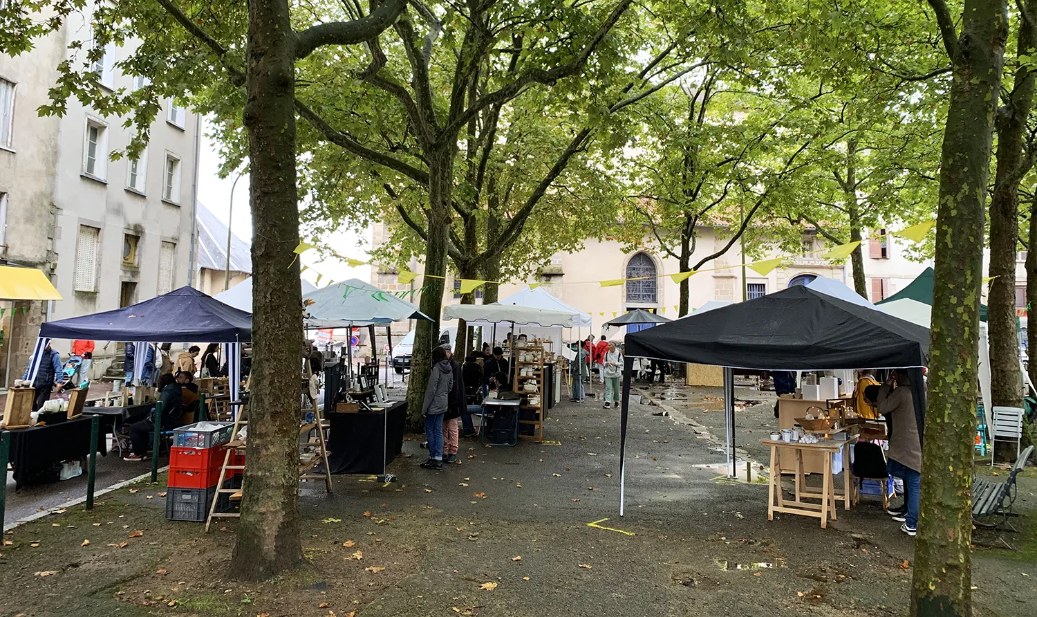 Marché de poterie à Limoges, sous les arbres, ambiance chaleureuse et artisanat local à l'honneur.